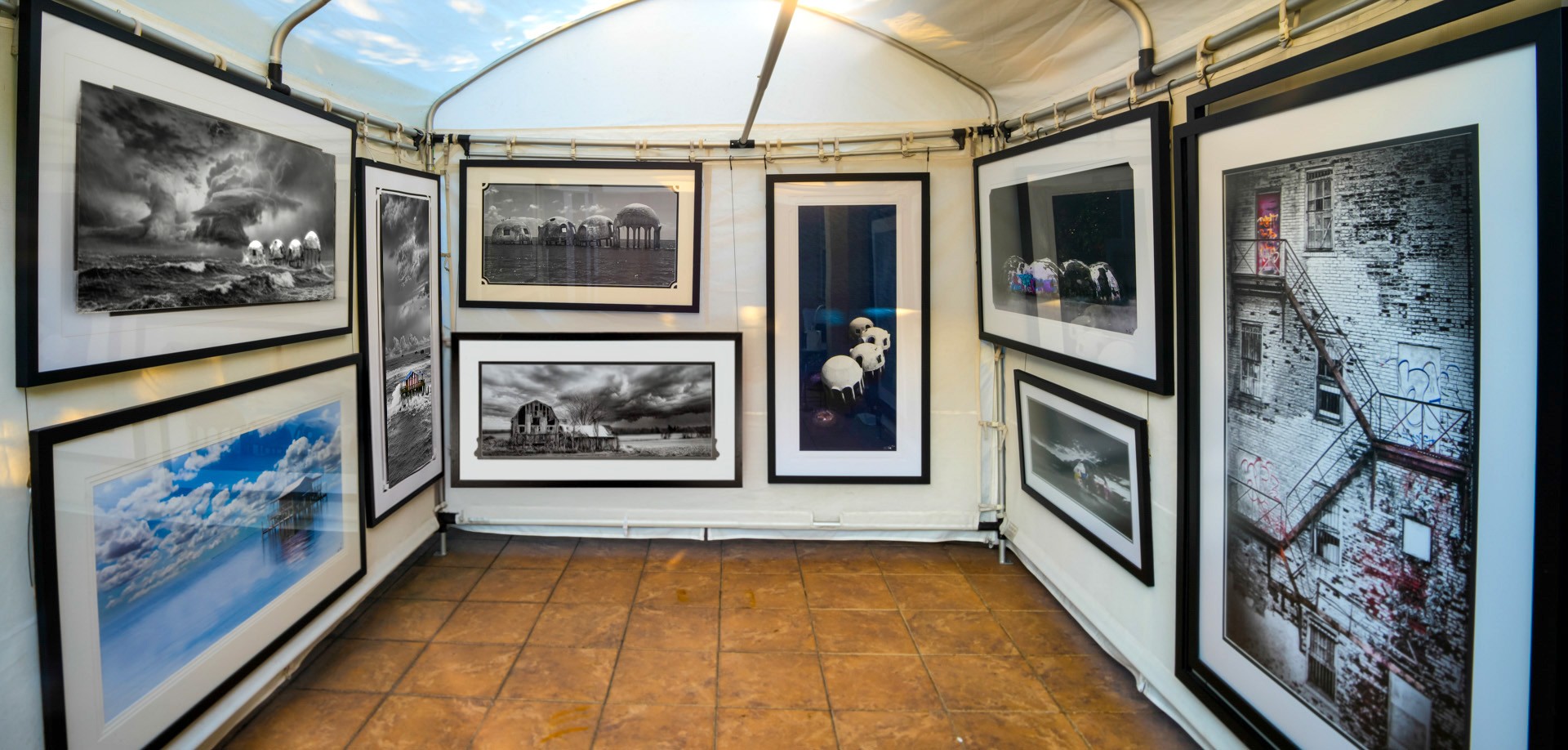 Inside Timothy Hall’s art show booth, with framed coastal and architectural photographs displayed on three walls